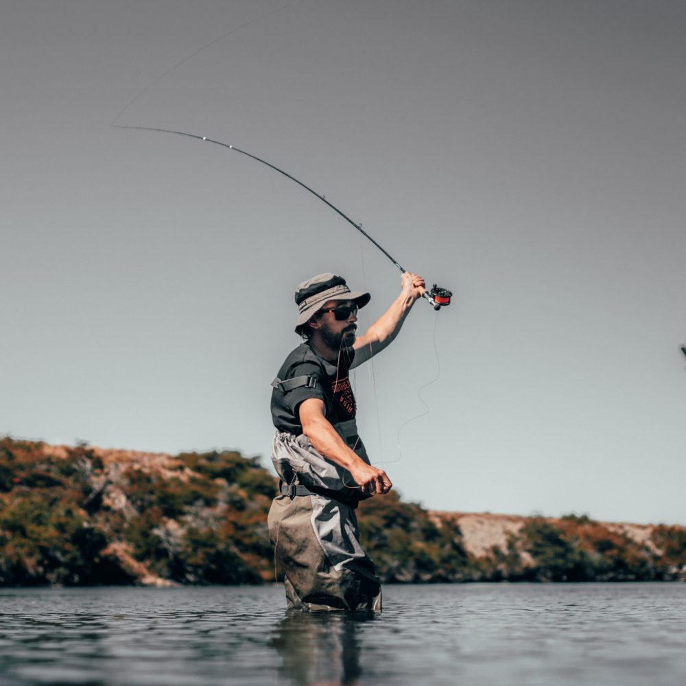 Man with sunglasses standing in river while fishing